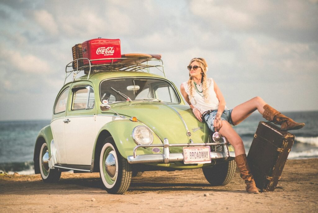 magia de lo retro, woman leaning on green and white Volkswagen Beetle near sea under white sky during daytime